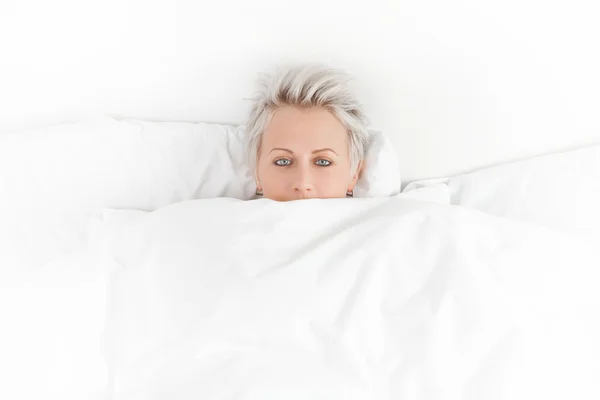 Pretty girl in bed hiding under the blanket — Stock Photo, Image