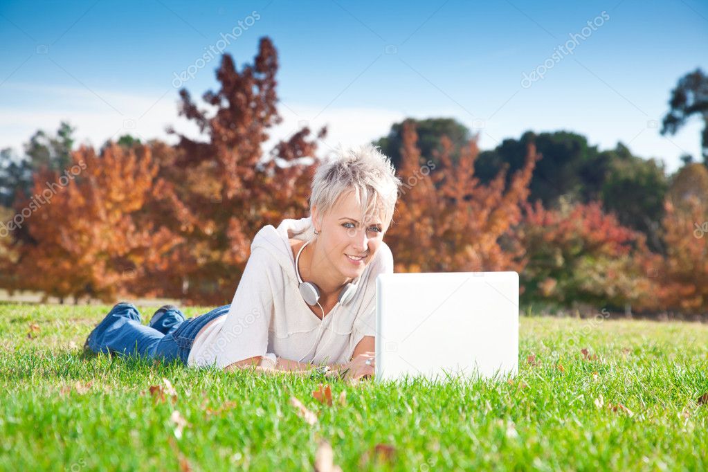 Smiling girl using laptop outdoors.