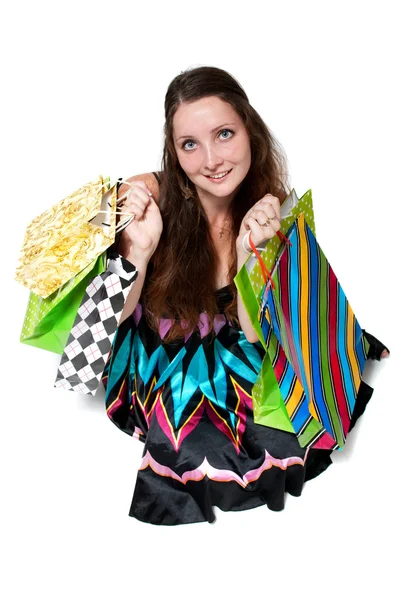 Молодая женщина в платье с красочными пакетами покупок на белой спине — стоковое фото