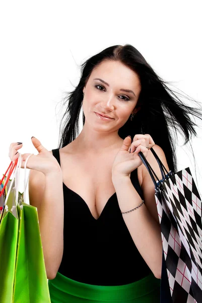 Jovem mulher em vestido com sacos de compras coloridos em uma parte traseira branca — Fotografia de Stock