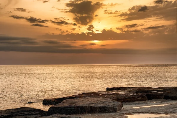 stock image Sun going down over water glowing on the shore