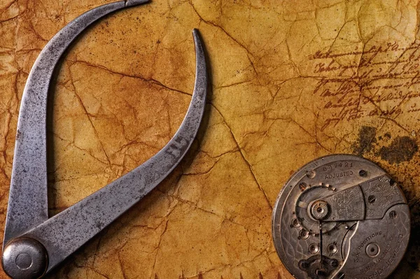 Antique tongs with a gears on the old textured paper — Stock Photo, Image