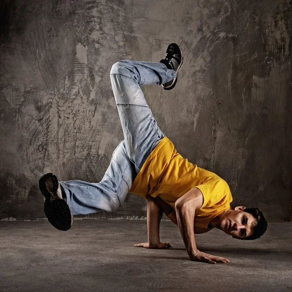 Young man dancing against grunge wall — Stock Photo, Image