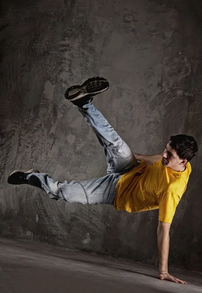 Young man dancing against grunge wall — Stock Photo, Image