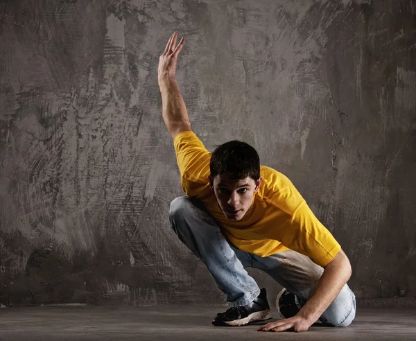 Jonge man dansen tegen grunge muur — Stockfoto