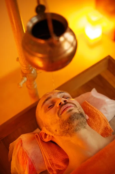 Homem fazendo uma massagem shirodhara em um salão — Fotografia de Stock