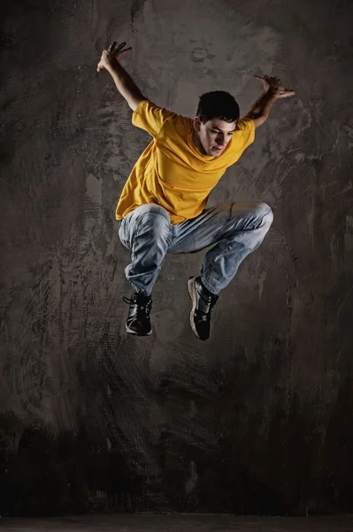 Young man jumping against grunge wall — Stock Photo, Image