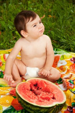 Baby eating watermelom outdoors. clipart