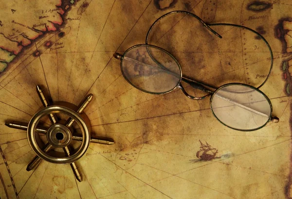 Glasses and sea wheel on the old map — Stock Photo, Image