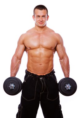 Portrait of strong man posing in gym with dumbbels clipart