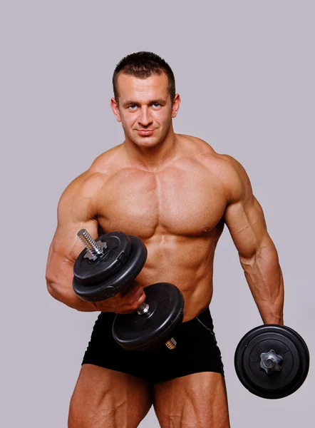 Портрет сильного мужчины, позирующего в спортзале с гантелями — стоковое фото