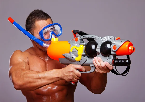 Kaslı adam ekipmanları yüzme ve su tabancası ile — Stok fotoğraf