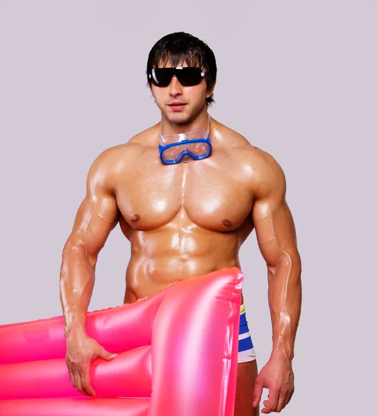 Portret van sexy man die zich voordeed op witte achtergrond met roze mattre — Stockfoto