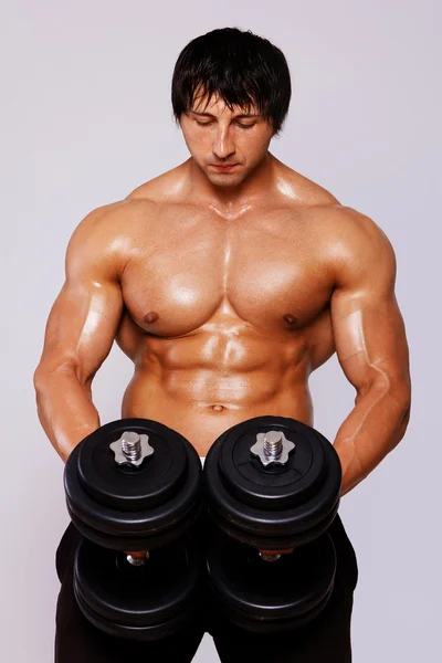 Porträt eines Muskelmannes, der im Studio auf grauem Hintergrund posiert — Stockfoto