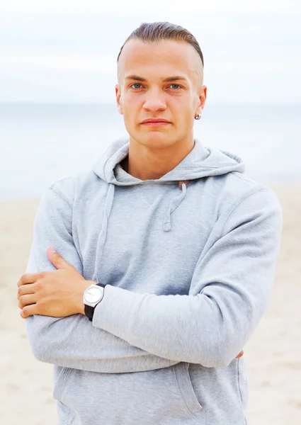 Portrét člověka pózuje na pláži v šedý kabát — Stock fotografie