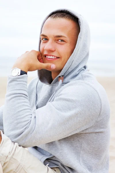 Portret van man glimlachend en zittend op het strand — Stockfoto