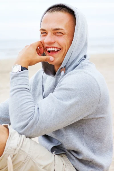 Retrato del hombre sentado en la playa en un abrigo — Foto de Stock