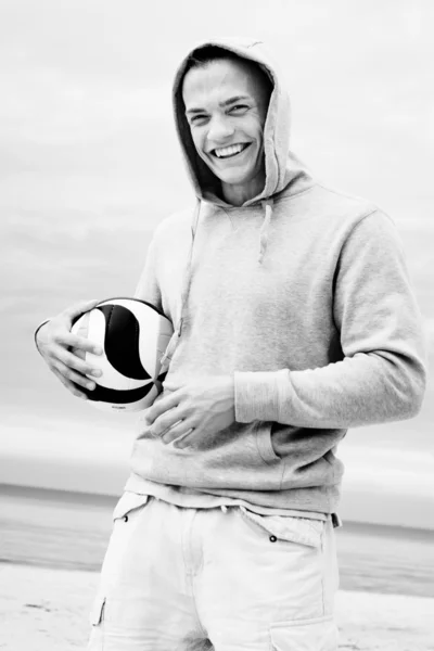 Portrét usmívajícího se muže pózuje na pláži s míčem — Stock fotografie