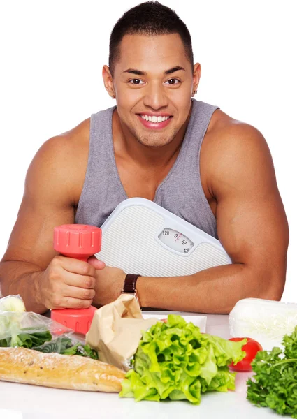 Retrato de homem muscular posando em estúdio com alimentos e halteres — Fotografia de Stock