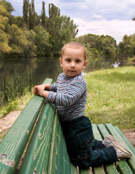 Мальчик на скамейке в парке — стоковое фото