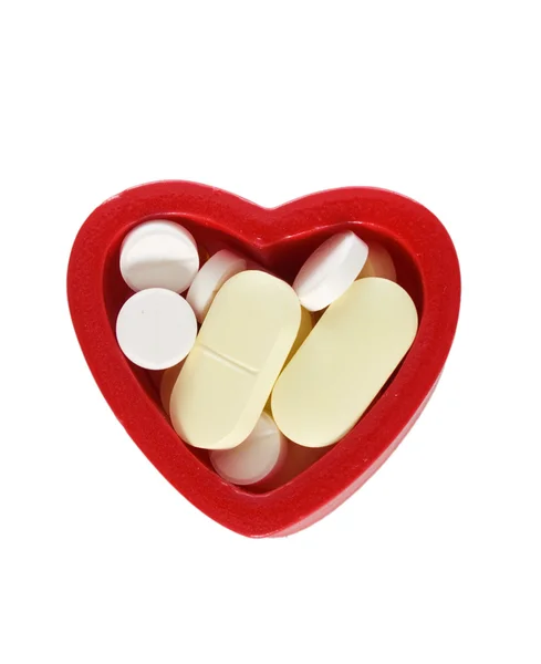 Красное сердце, полное таблеток — стоковое фото
