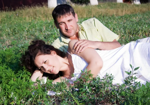 Retrato de una hermosa joven tumbada en la hierba con su novio —  Fotos de Stock