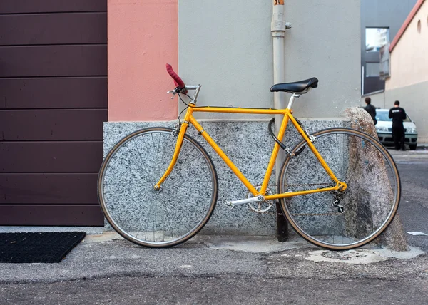 Bicicleta amarela amarrada ao poste — Fotografia de Stock