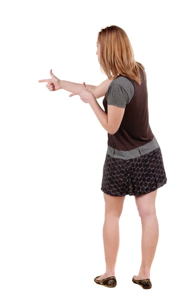 Back view of young blonde woman pointing at wall . — Stock Photo, Image