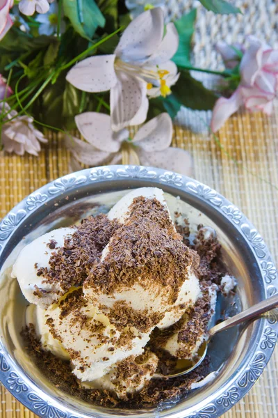 Zoet dessert met de geraspte chocolade en boeket met bloemen — Stockfoto