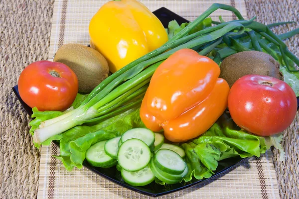 Las frutas y verduras de colores varicolores se encuentran en un plato —  Fotos de Stock