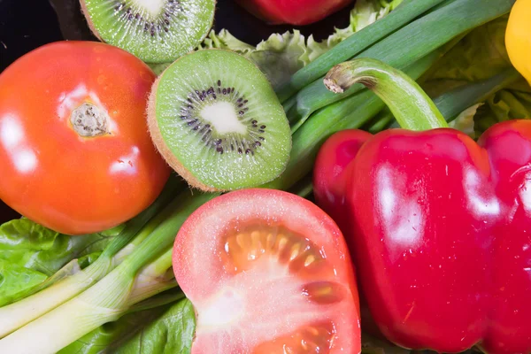 Las frutas y verduras de colores varicolores se encuentran en un plato —  Fotos de Stock