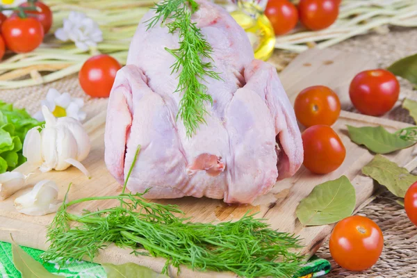 Carcaça de frango em uma tábua de madeira com tomates e greene fresco — Fotografia de Stock