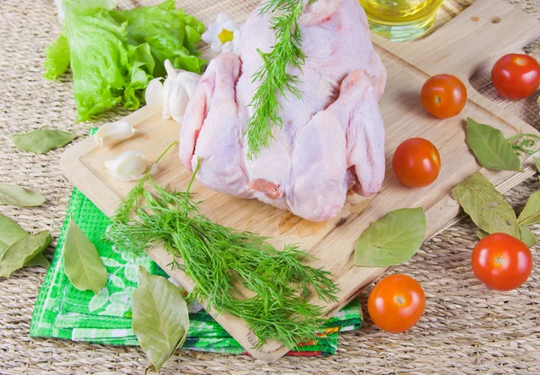 Carcaça de frango em uma tábua de madeira com tomates e greene fresco — Fotografia de Stock