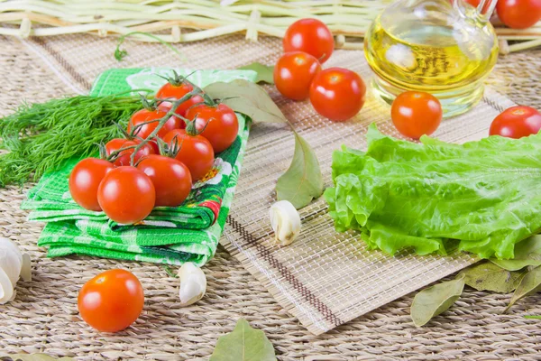 Tomates rojos maduros con vegetación fresca en una servilleta —  Fotos de Stock