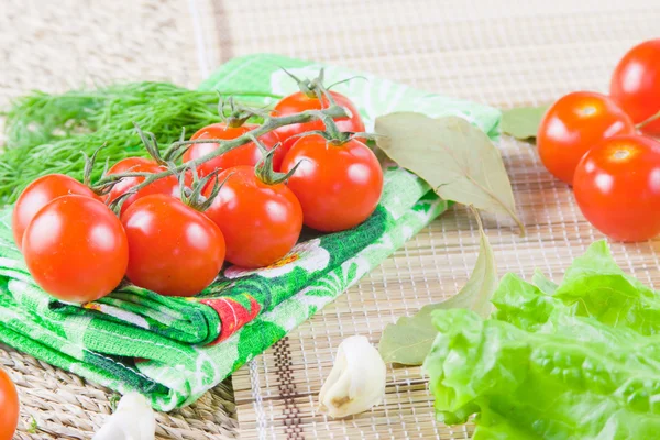 Tomates rojos maduros con vegetación fresca en una servilleta —  Fotos de Stock