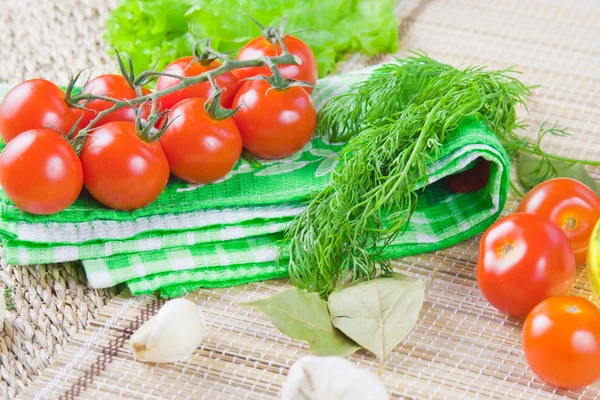 Červená zralá rajčata s čerstvou zelení na ubrousku — Stock fotografie