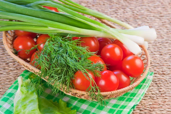 Tomates rojos maduros con vegetación fresca en una servilleta — Foto de Stock