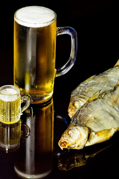 stock image Two mugs with beer and dried fish on a black background