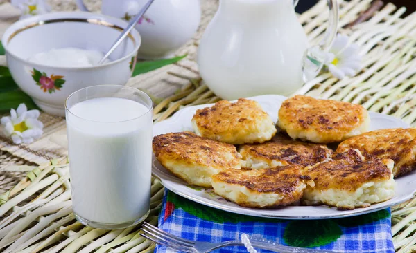 Stekt ostmassa pannkakorna på ett fat och mjölk — Stockfoto