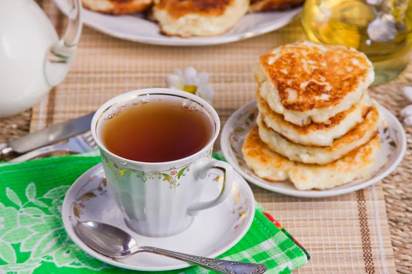 Tasse mit Tee, Quark-Pfannkuchen auf einem Teller und Milch — Stockfoto