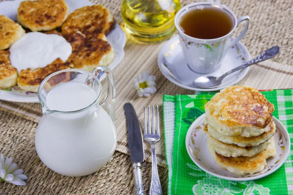 Csésze tea, palacsintát egy edénybe, és a tej túró — Stock Fotó