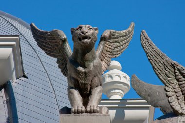 Aslan üzerinde arka plan mavi bir binanın çatısında heykeller
