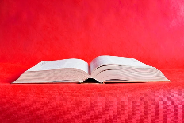Velká otevřená kniha na červeném pozadí — Stock fotografie