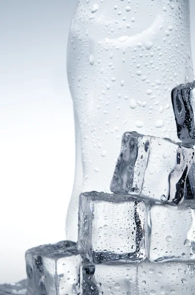 Cubos de gelo e garrafa de água mineral close-up — Fotografia de Stock