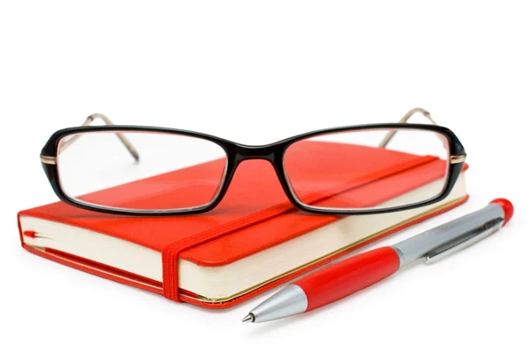 Bloc de notas rojo cerrado, gafas y bolígrafo aislados en blanco — Foto de Stock
