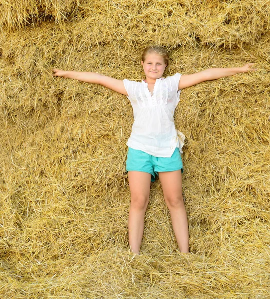 Girl on the background of the large stack of hay — Stock Photo, Image