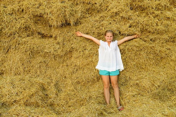 Girl on the background of the large stack of hay — Stock Photo, Image