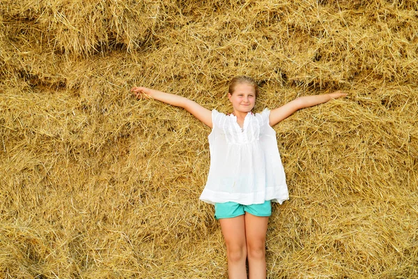 Girl on the background of the large stack of hay Royalty Free Stock Images