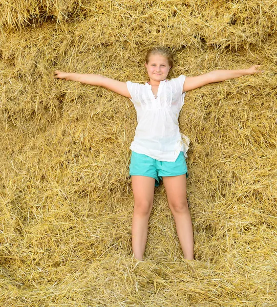 Girl on the background of the large stack of hay Stock Photo