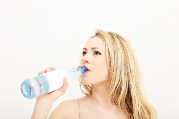 Ung kvinna dricker ur en flaska vatten Stockbild